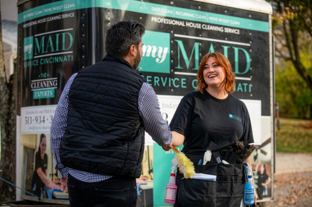 Two My Maid Service team members greeting each other by the branded van